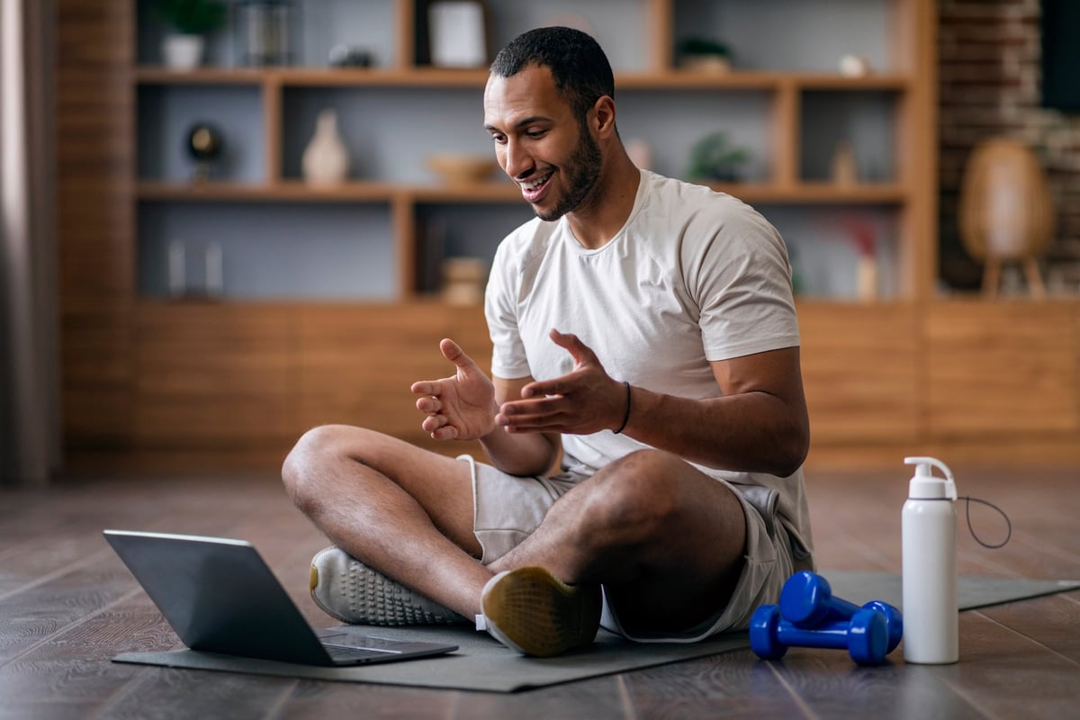 Teilnehmer eines Online-Trainingskurses trainiert zu Hause vor dem Laptop